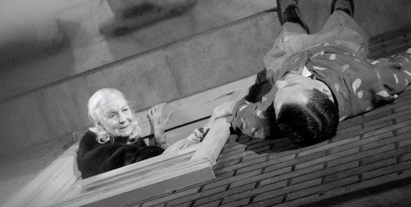 A woman talking to a man on a ledge of a building