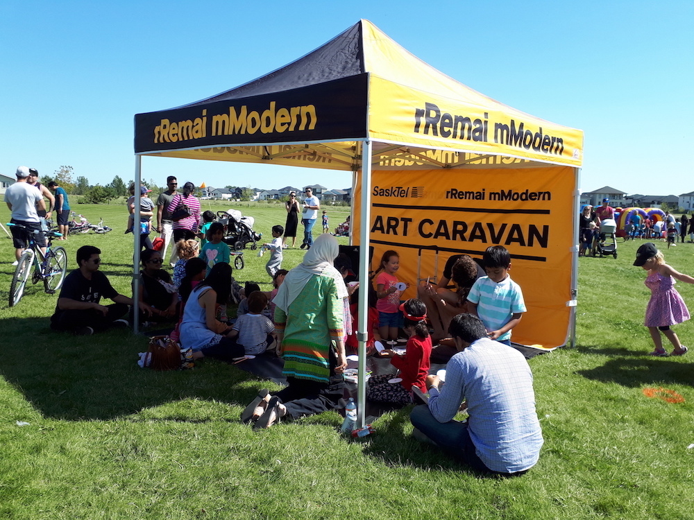 An outdoor tent on a grass field with people