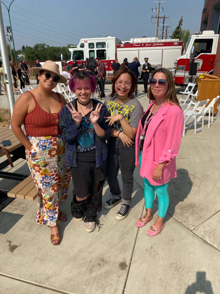 A group of staff and students pose together at the opening for a new fire hall in Saskatoon. A fire truck can be seen in the background.