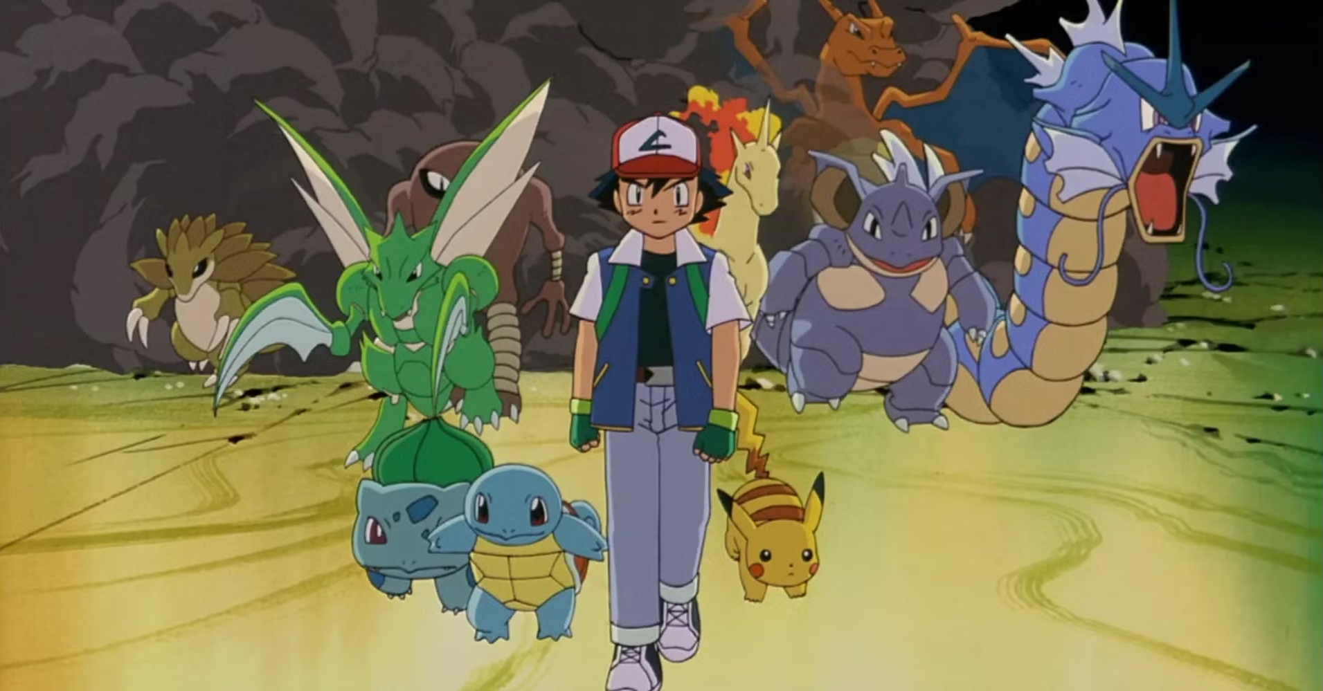 A determined-looking Ash Ketchum walks forward confidently, surrounded by a group of Pokémon including Pikachu, Squirtle, Bulbasaur, Scyther, Sandshrew, Charizard, Gyarados, and others. The background is a rocky cave-like environment with dramatic lighting, emphasizing the unity and readiness of the team for an impending challenge. The image is from the animated film "Pokémon: The First Movie."